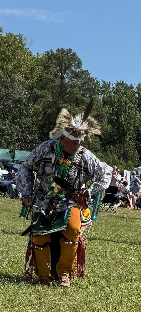 A traditional dancer in feather bustle and beaded regalia on the field at the powwow