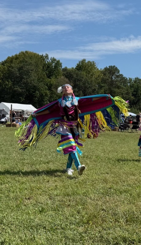 A young dancer spreading a bright fringed shawl like wings in the arena