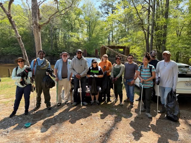 Volunteers posing together with trash bags and grabbers after a cleanup