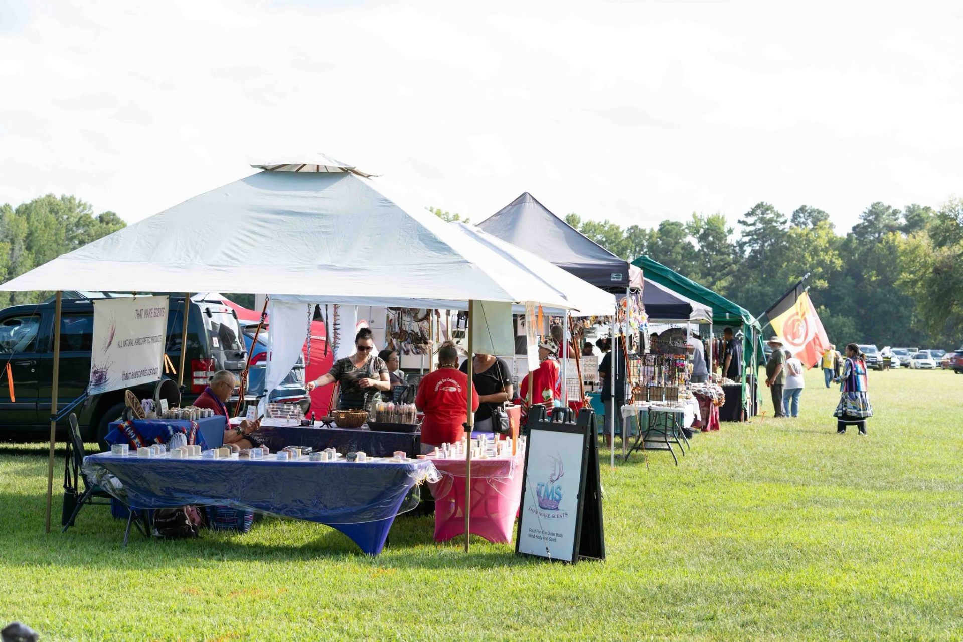 A row of vendor tents and craft tables across the powwow field